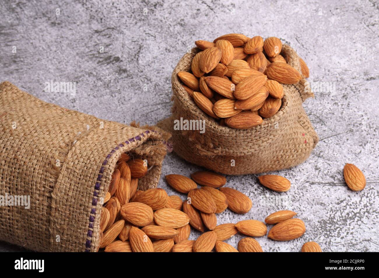 Mandorle in sacchetto isolate su sfondo grigio. Foto Stock