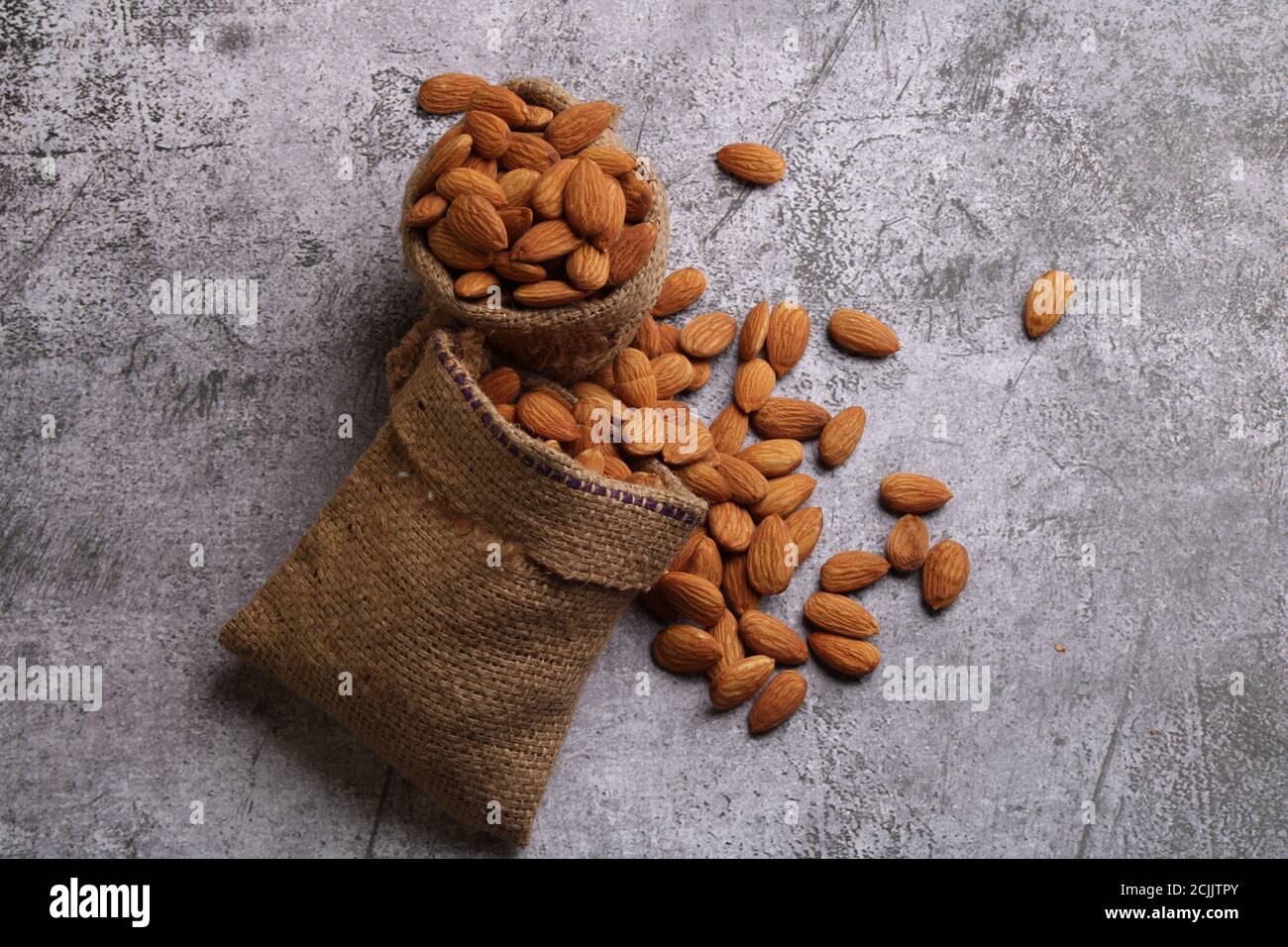 Mandorle in sacchetto isolate su sfondo grigio. Foto Stock