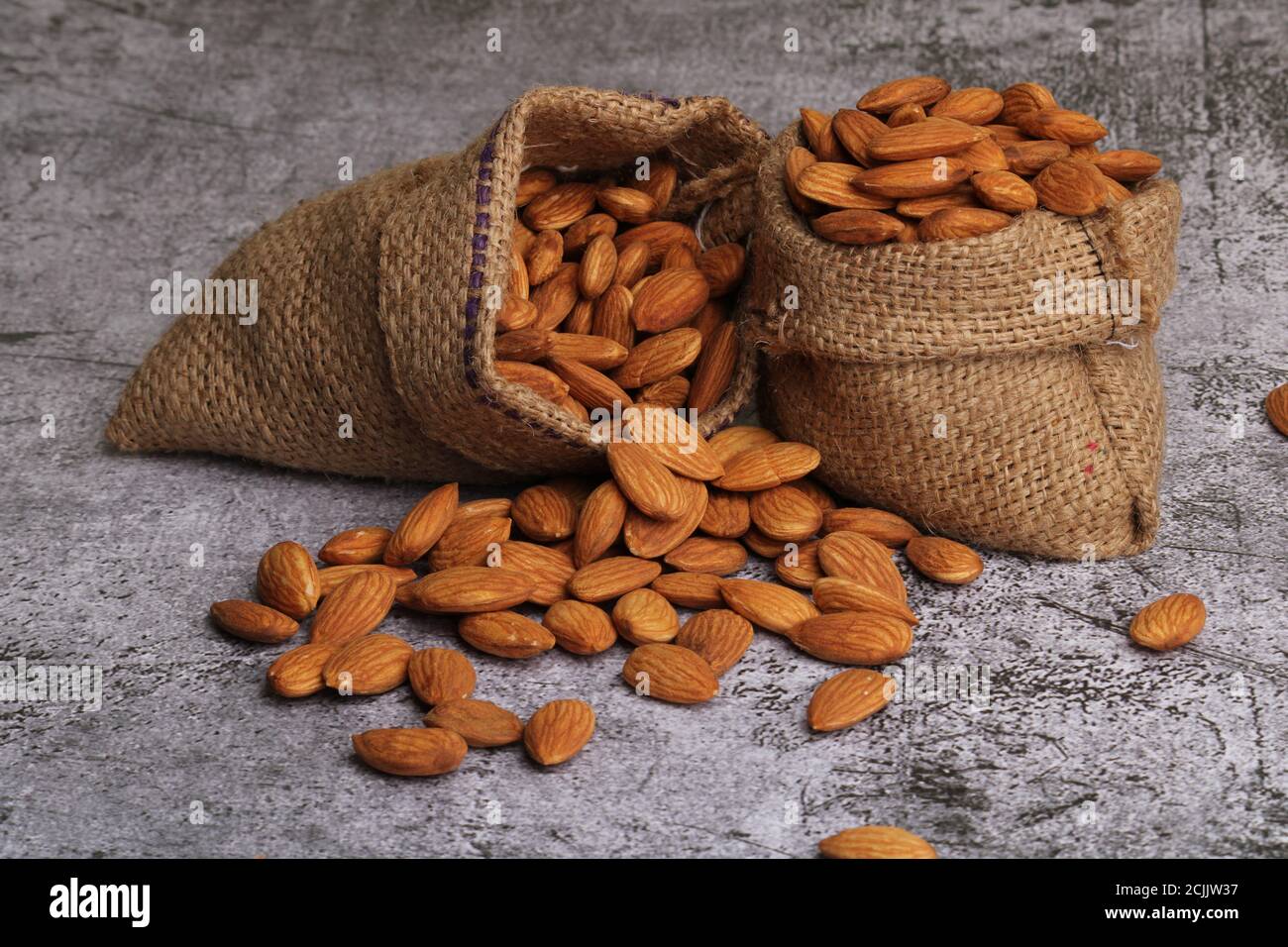 Mandorle in sacchetto isolate su sfondo grigio. Foto Stock