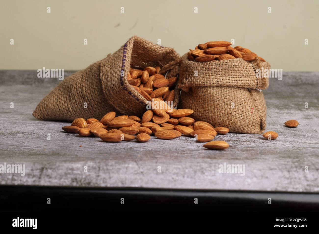 Mandorle in sacchetto isolate su sfondo grigio. Foto Stock