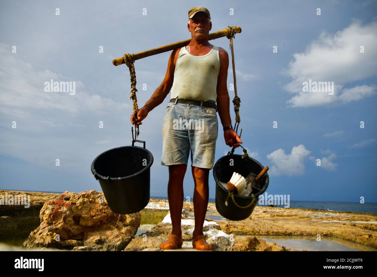 Gozo, Malta. 7 Settembre 2020. Alfred Attard, che da quasi cinque decenni raccoglie il sale marino, trasporta secchi di sale in un villaggio di Gozo, Malta, il 7 settembre 2020. Circondata interamente dal mare, Malta è un grande produttore di sale marino attraverso saline scavate nella roccia. Credit: Jonathan Borg/Xinhua/Alamy Live News Foto Stock