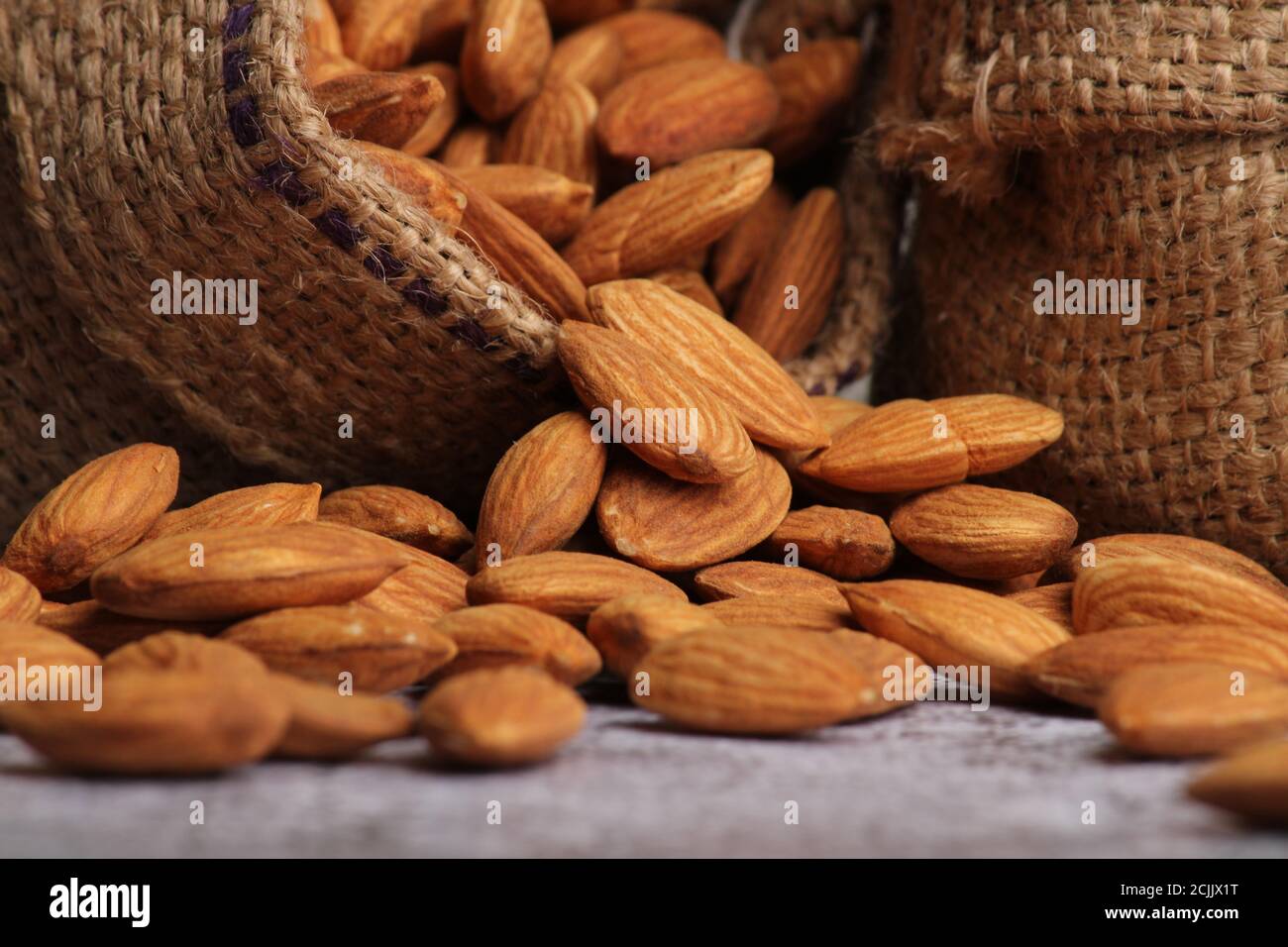 Mandorle in sacchetto isolate su sfondo grigio. Foto Stock