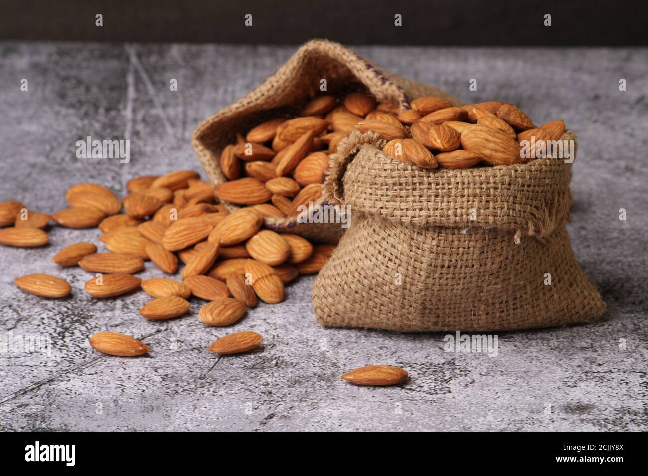 Mandorle in sacchetto isolate su sfondo grigio. Foto Stock