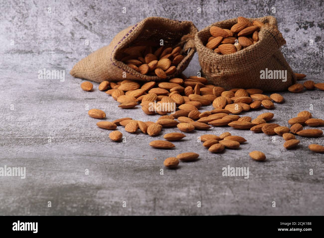 Mandorle in sacchetto isolate su sfondo grigio. Foto Stock