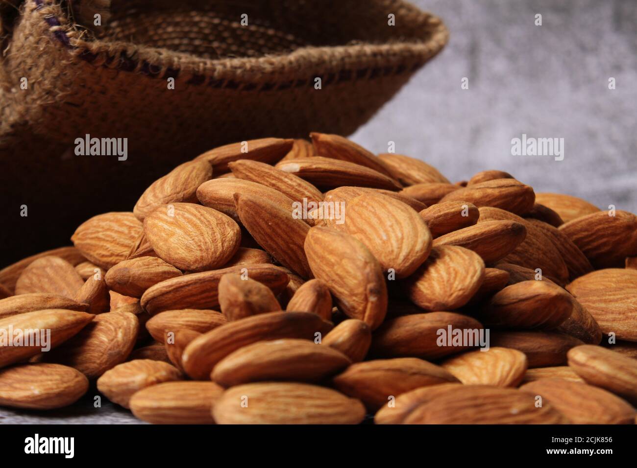 Mandorle in sacchetto isolate su sfondo grigio. Foto Stock