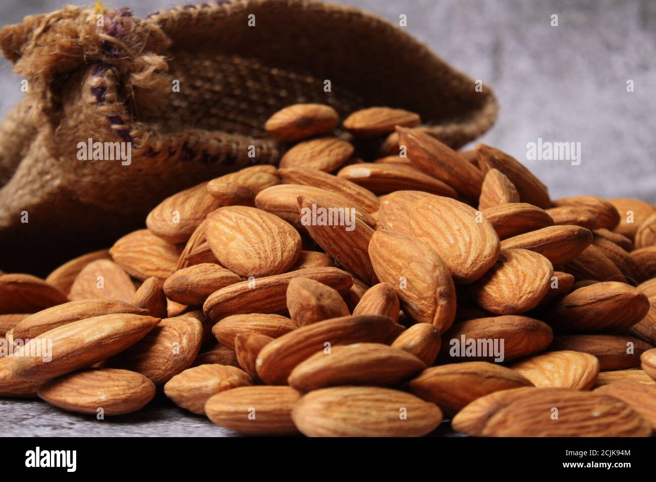 Mandorle in sacchetto isolate su sfondo grigio. Foto Stock