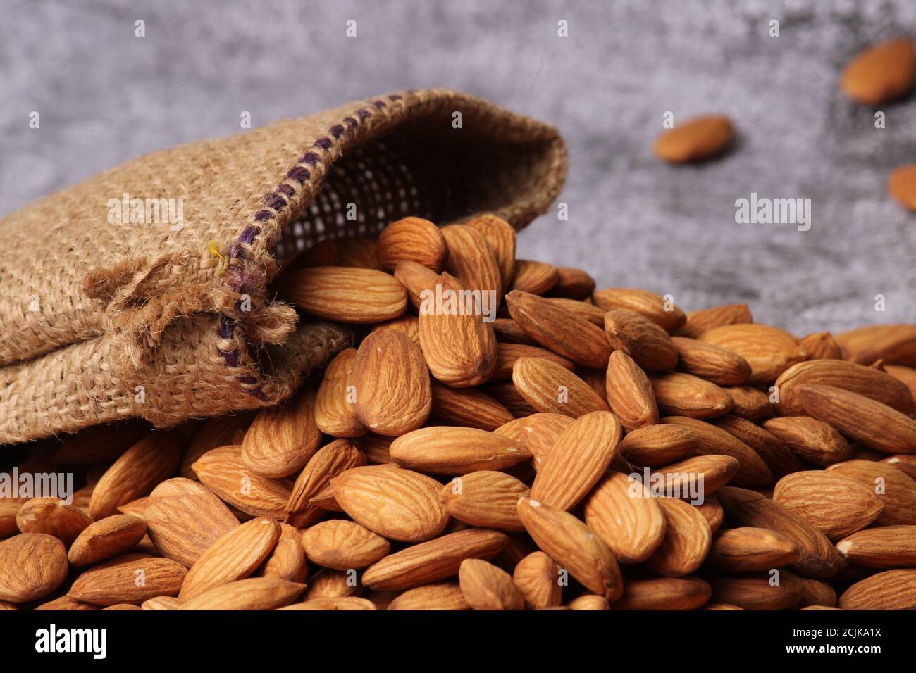 Mandorle in sacchetto isolate su sfondo grigio. Foto Stock