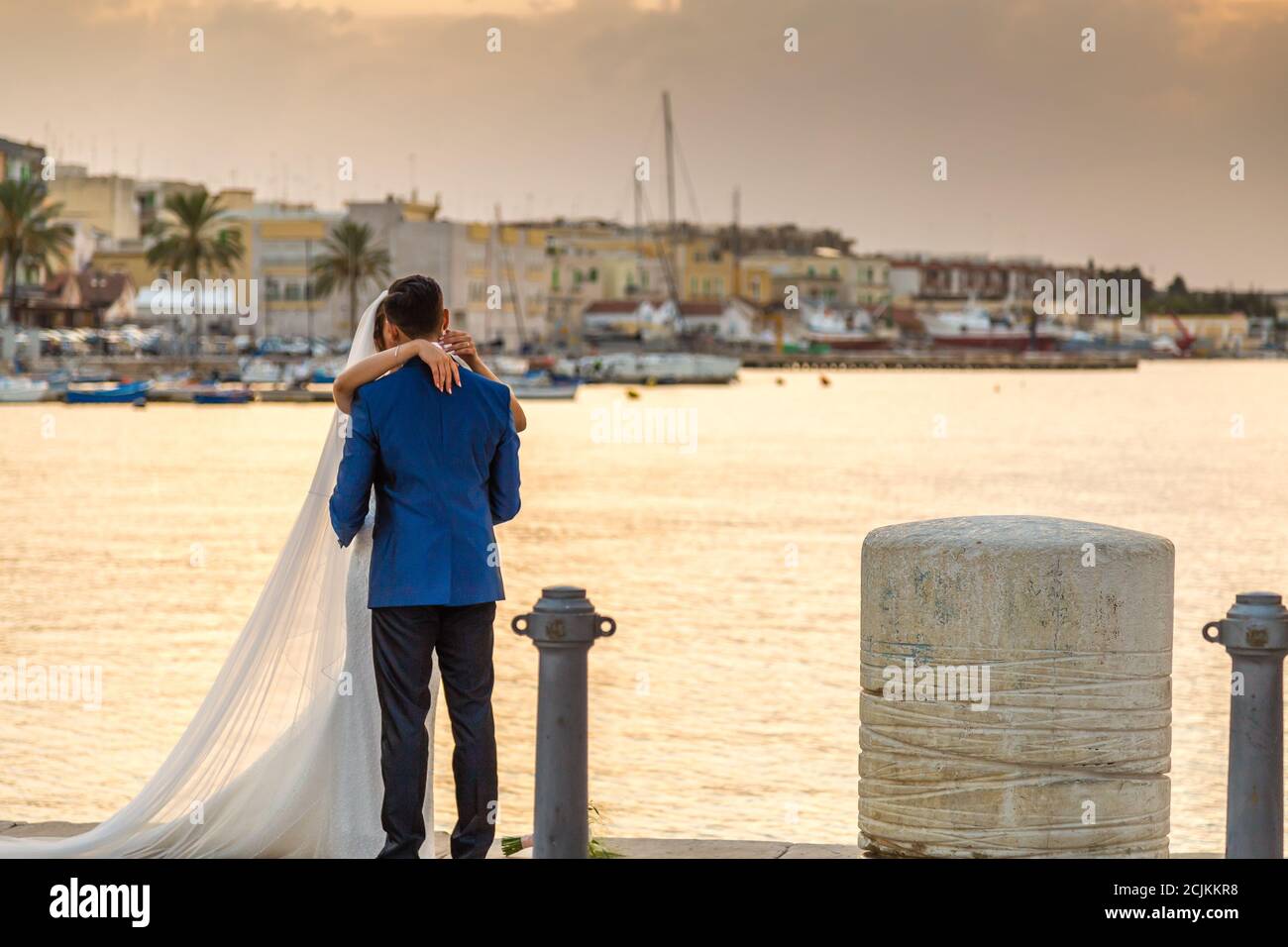 Sposi novelli baciando sotto il tramonto sul mare di ​​Molfetta Foto Stock