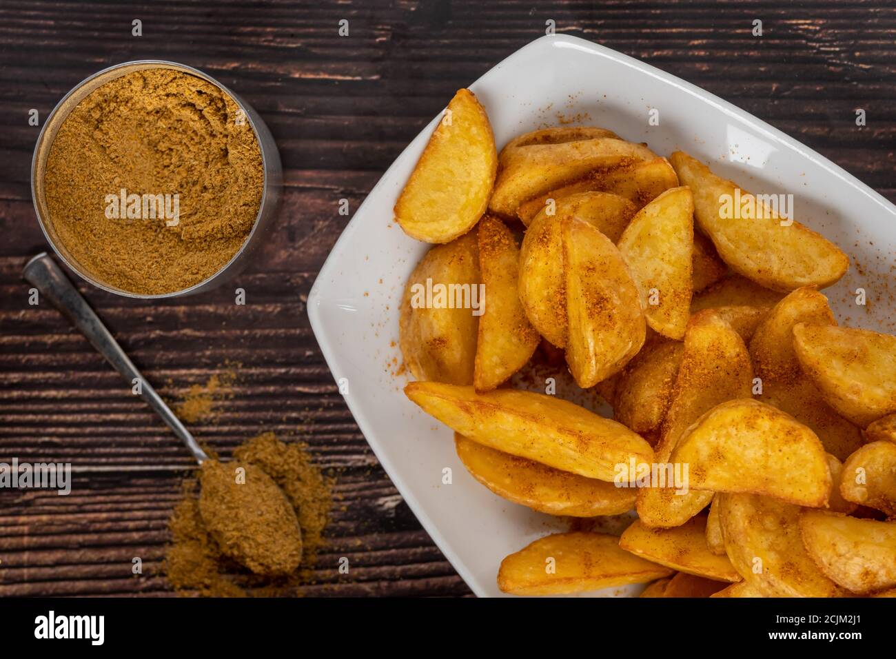 Patate a zeppa piccanti su piatto bianco su tavolo di legno Foto Stock