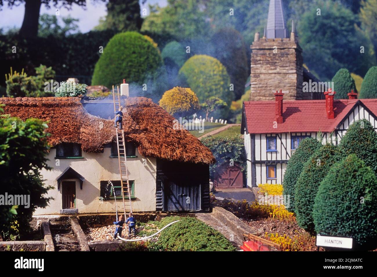 Modello vigili del fuoco assistere a un fuoco in un cottage di paglia in Hanton borgo, Bekonscot modello villaggio e ferrovia, Bekonscot modello Village. Beaconsfield. Buckinghamshire, Chilterns, Inghilterra, Regno Unito Foto Stock