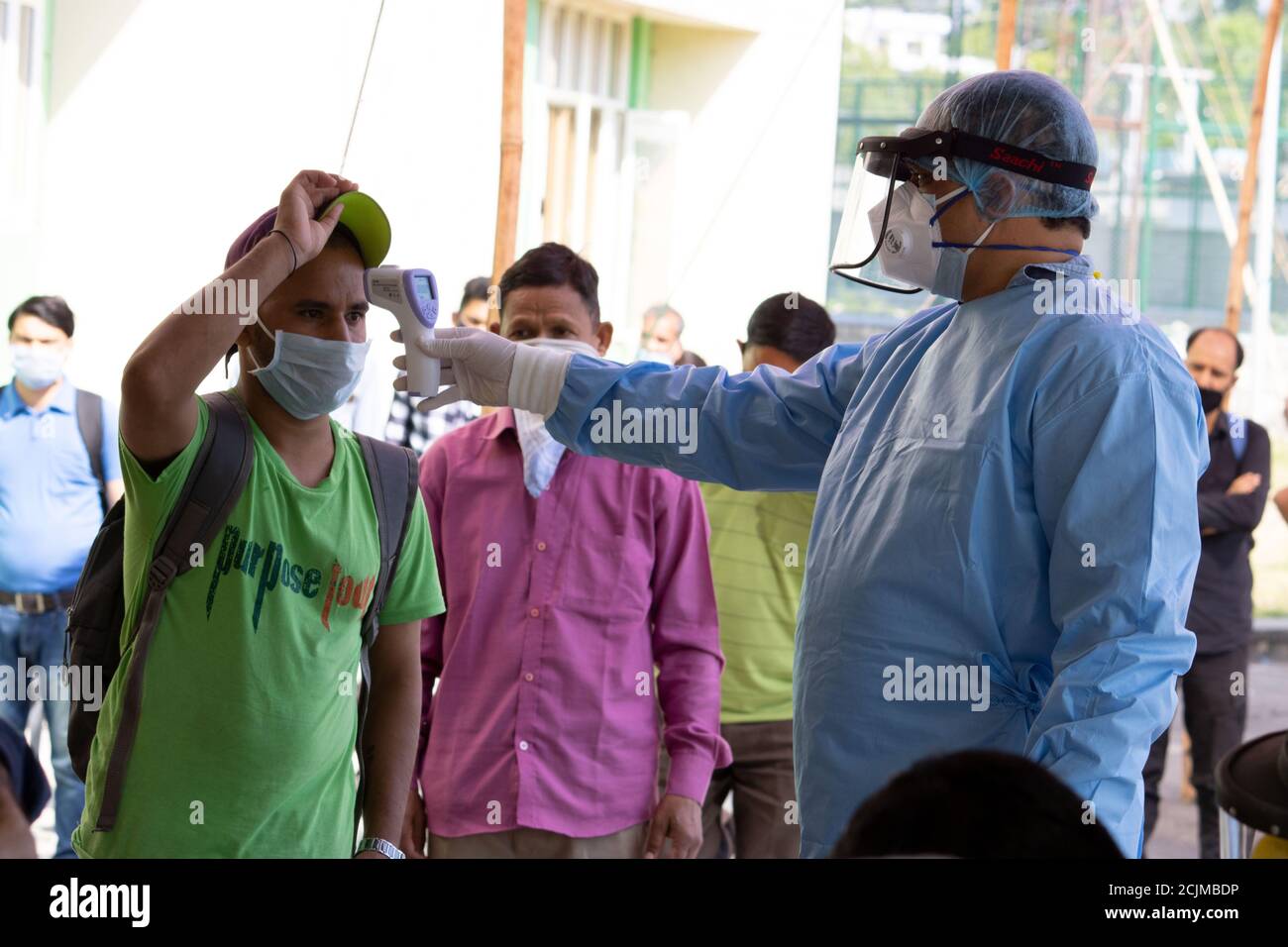 Dehradun, Uttarakhand/India - 10 2020 settembre: Un medico che controlla la temperatura della gente migrante, indossando il kit PPE e la protezione del viso. Foto Stock