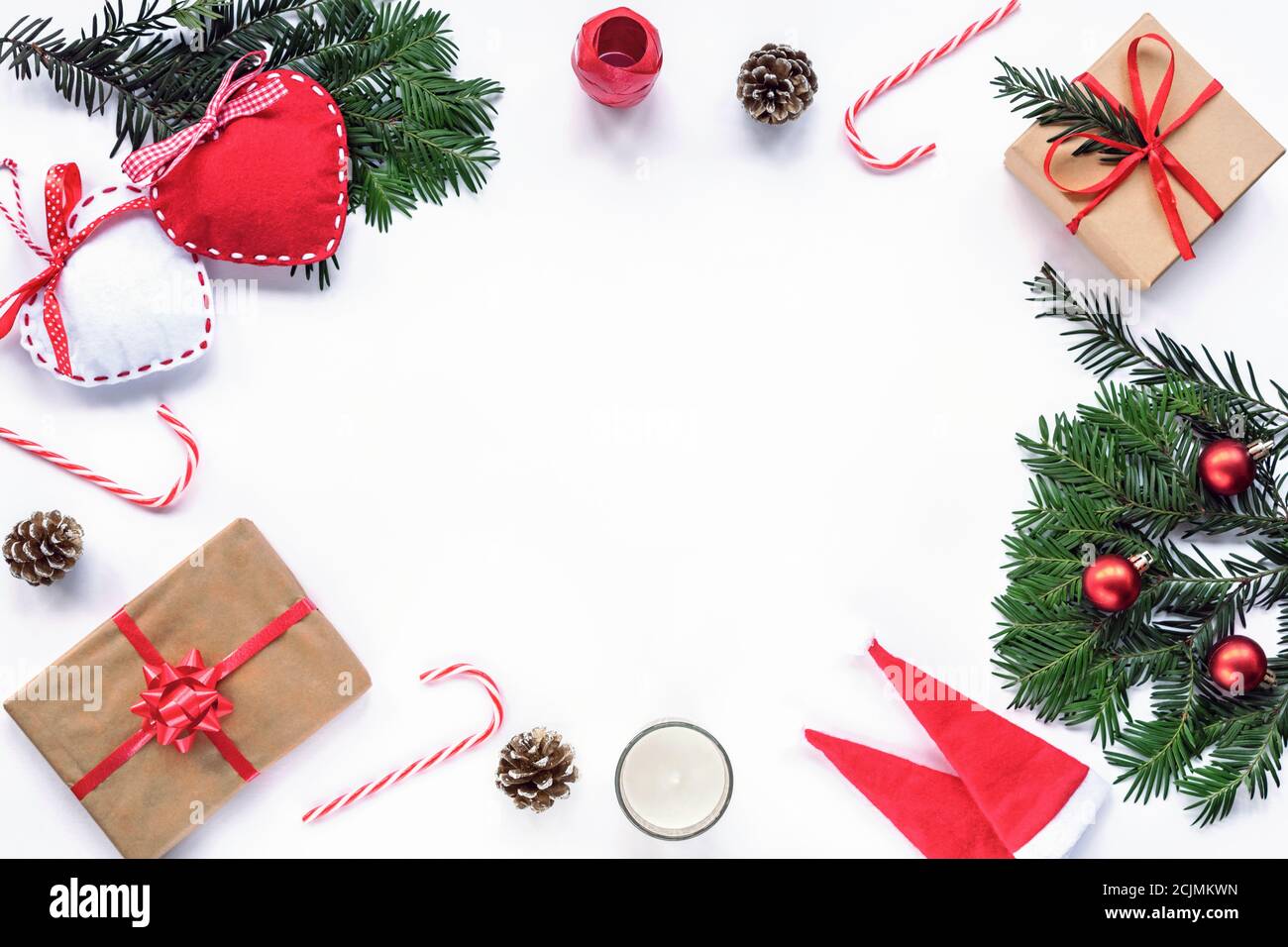 Cornice di Natale fatta di rami di abete, caramelle rosse, coni, cappelli di Babbo Natale, regalo in una scatola, decorazioni. Natale o Capodanno. Disposizione piatta, parte superiore Foto Stock
