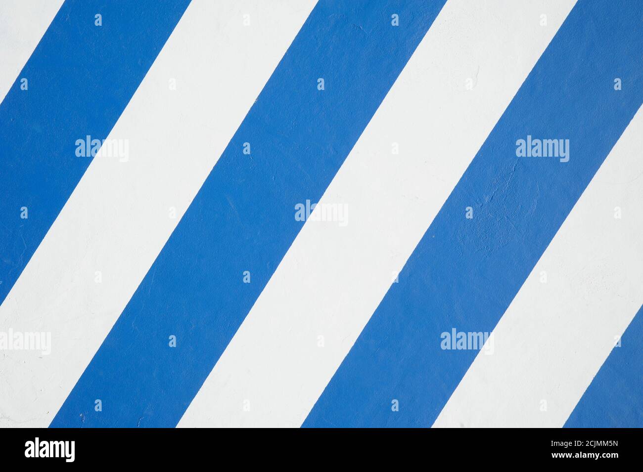 Sfondo di una parete con strisce diagonali blu e bianche, segni di vernice e spazio di copia. Sfondo astratto con ripetizione lineare simmetrica Foto Stock