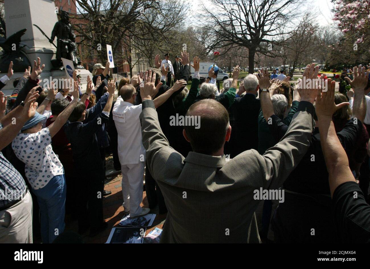 I manifestanti religiosi contro la guerra alzano le mani in preghiera, di fronte alla Casa Bianca, prima di essere arrestati nel Lafayette Park di Washington, il 26 marzo 2003. Più di 60 persone sono state arrestate nell'azione non violenta di disobbedienza civile, organizzata da gruppi religiosi e di pace, per protestare contro la guerra in Iraq. REUTERS/Jim Bourg JRB/GN Foto Stock