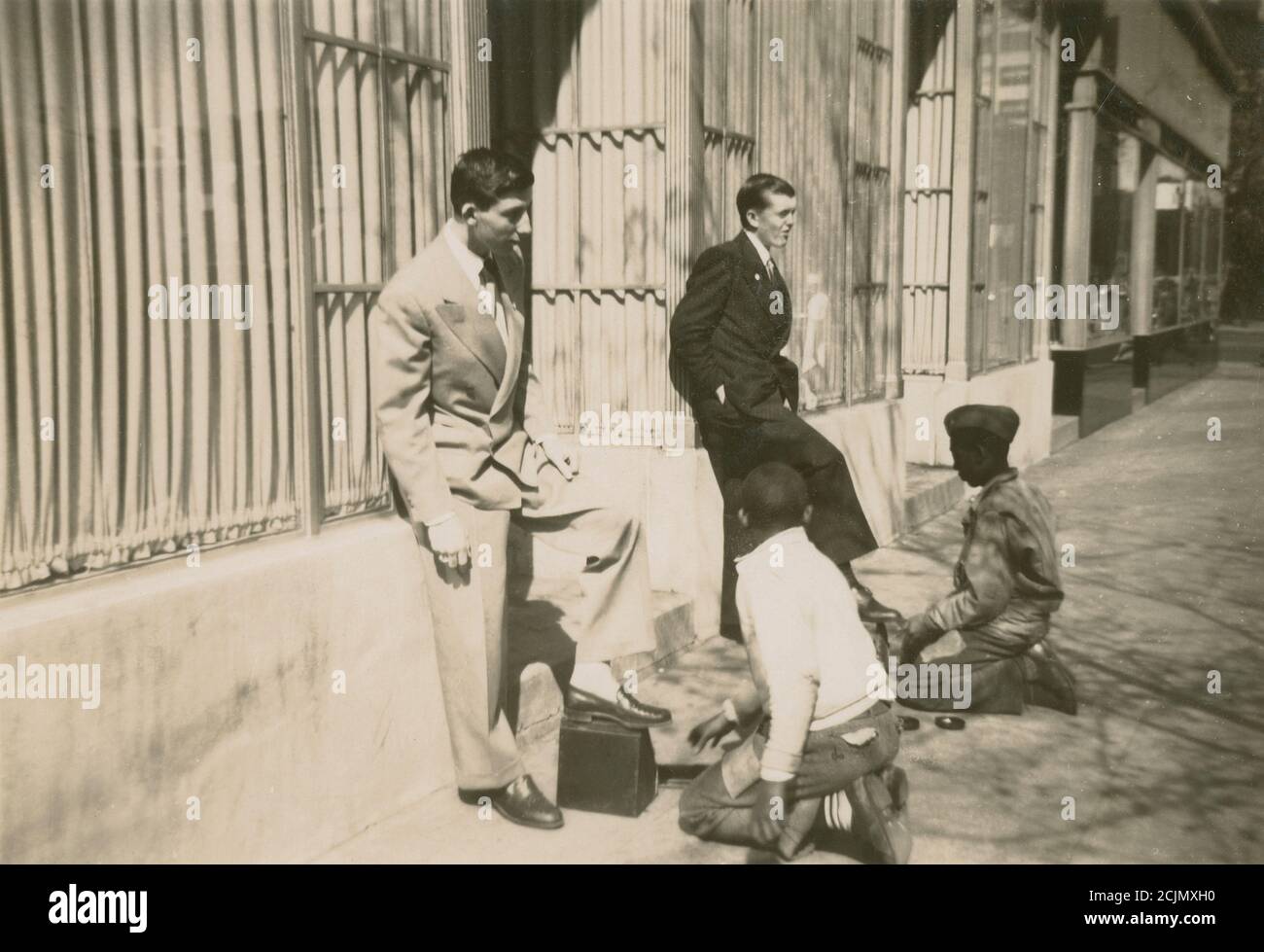 Antica fotografia c1940, due giovani uomini che hanno le loro scarpe brillate da ragazzi afroamericani su una strada cittadina. Posizione esatta sconosciuta, probabilmente New England, USA. FONTE: FOTOGRAFIA ORIGINALE Foto Stock