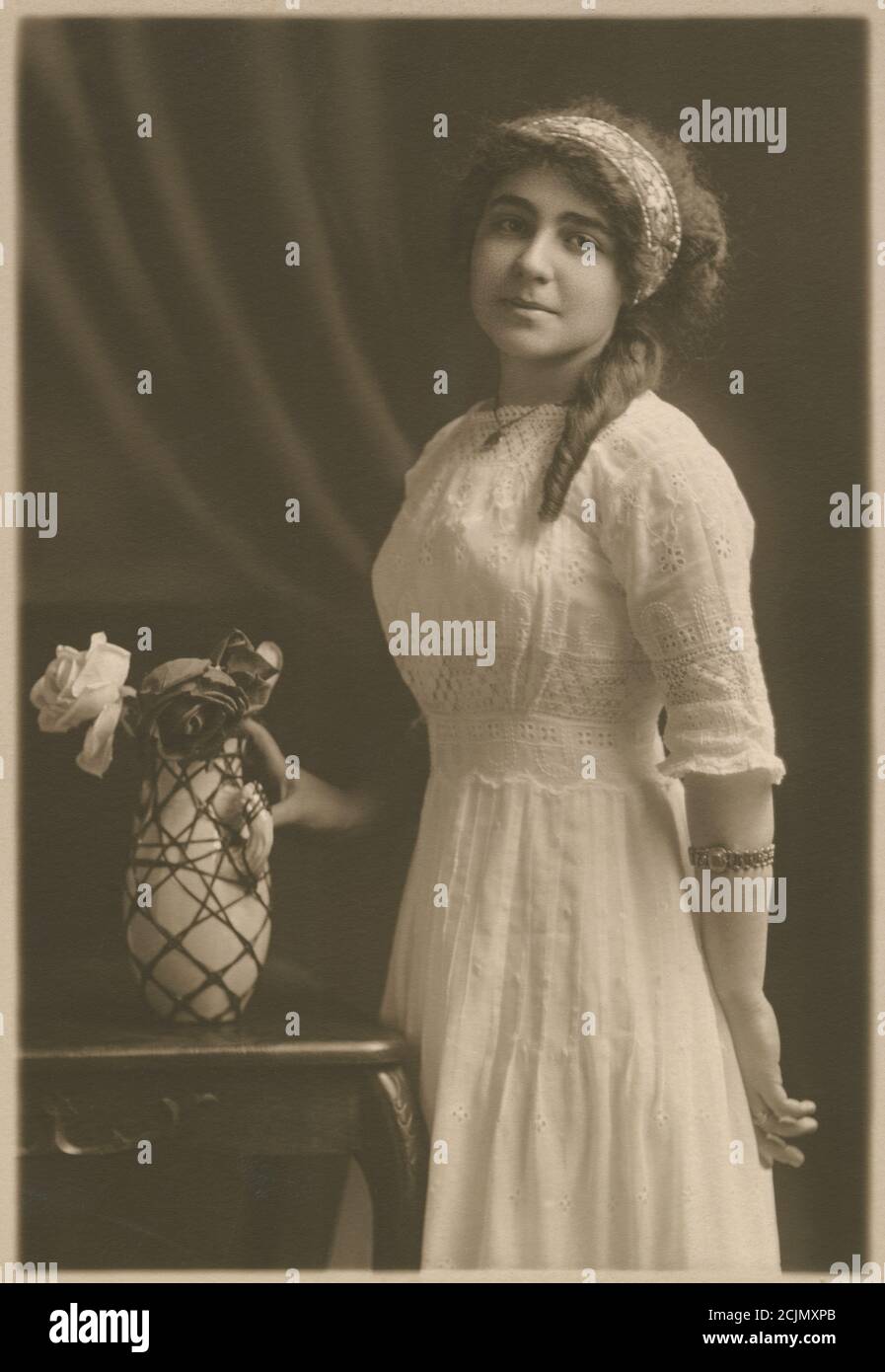 Antica fotografia c1920, ritratto di una donna, età circa 20-24, con un vaso di fiori. Posizione esatta sconosciuta, probabilmente New England, USA. FONTE: FOTOGRAFIA ORIGINALE Foto Stock