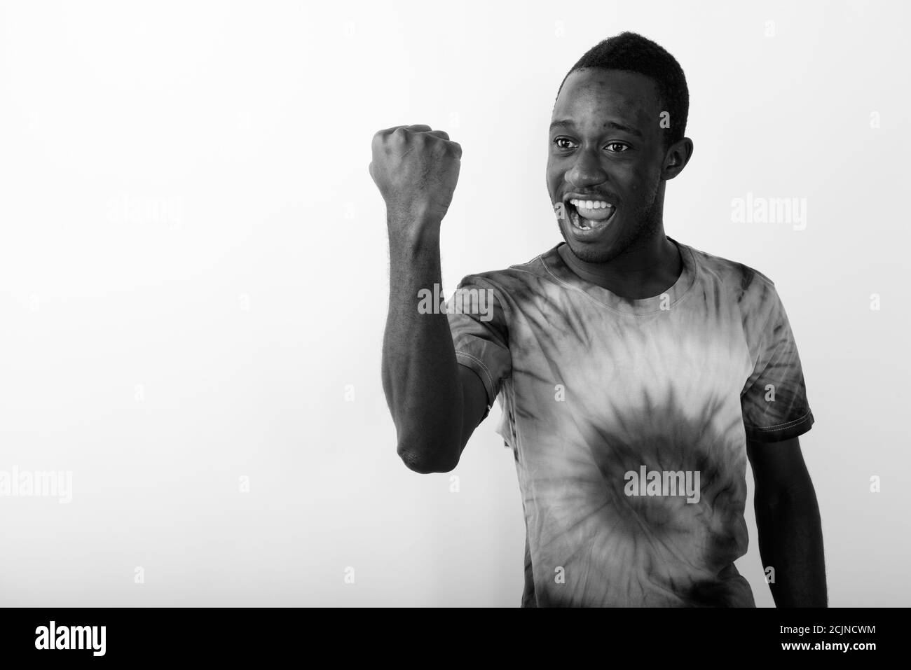 Studio girato di giovane felice uomo nero africano con Raised braccio che guarda eccitato contro sfondo bianco Foto Stock