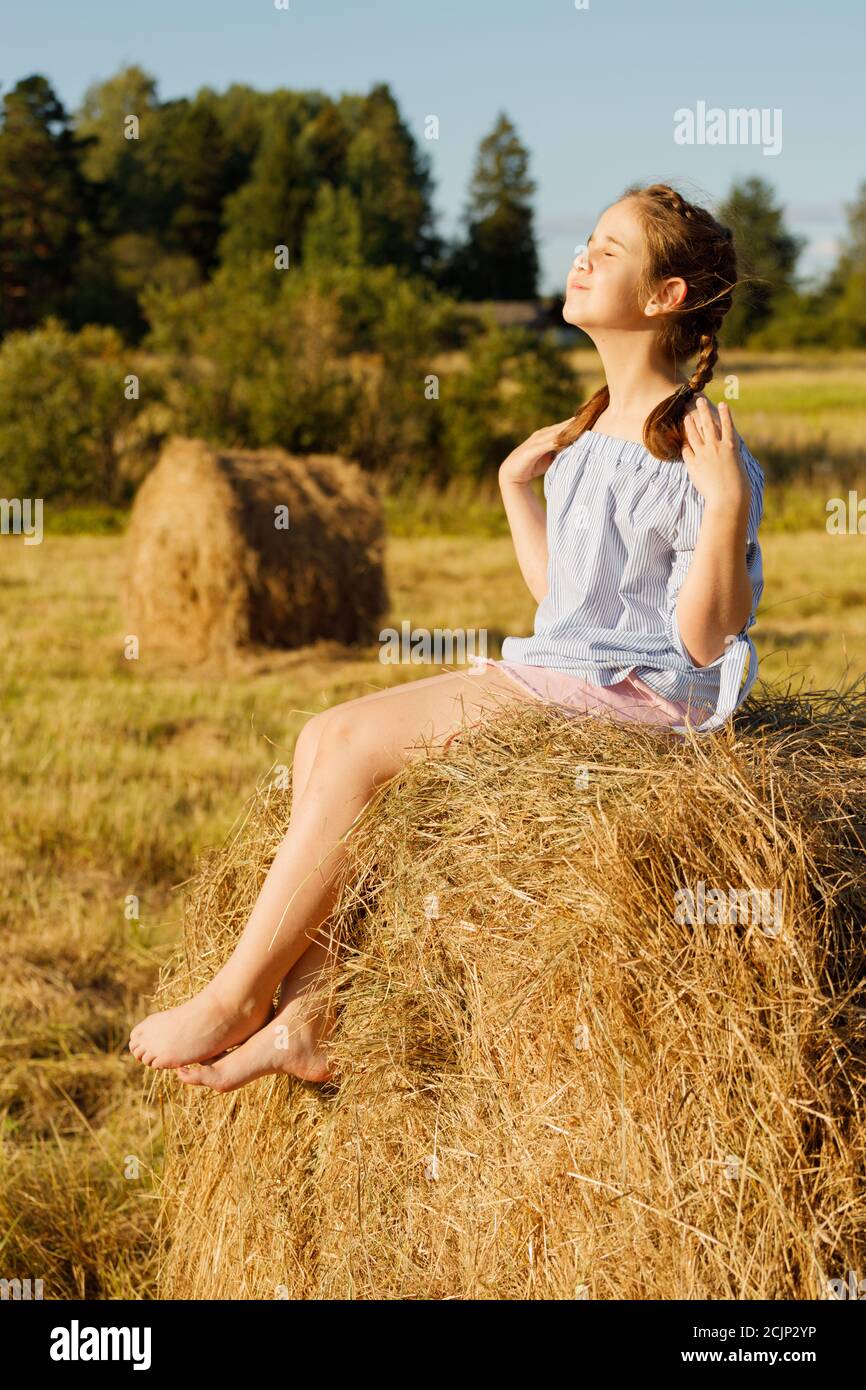 giovane ragazza in un campo estivo. su un rotolo di fieno. Foto Stock