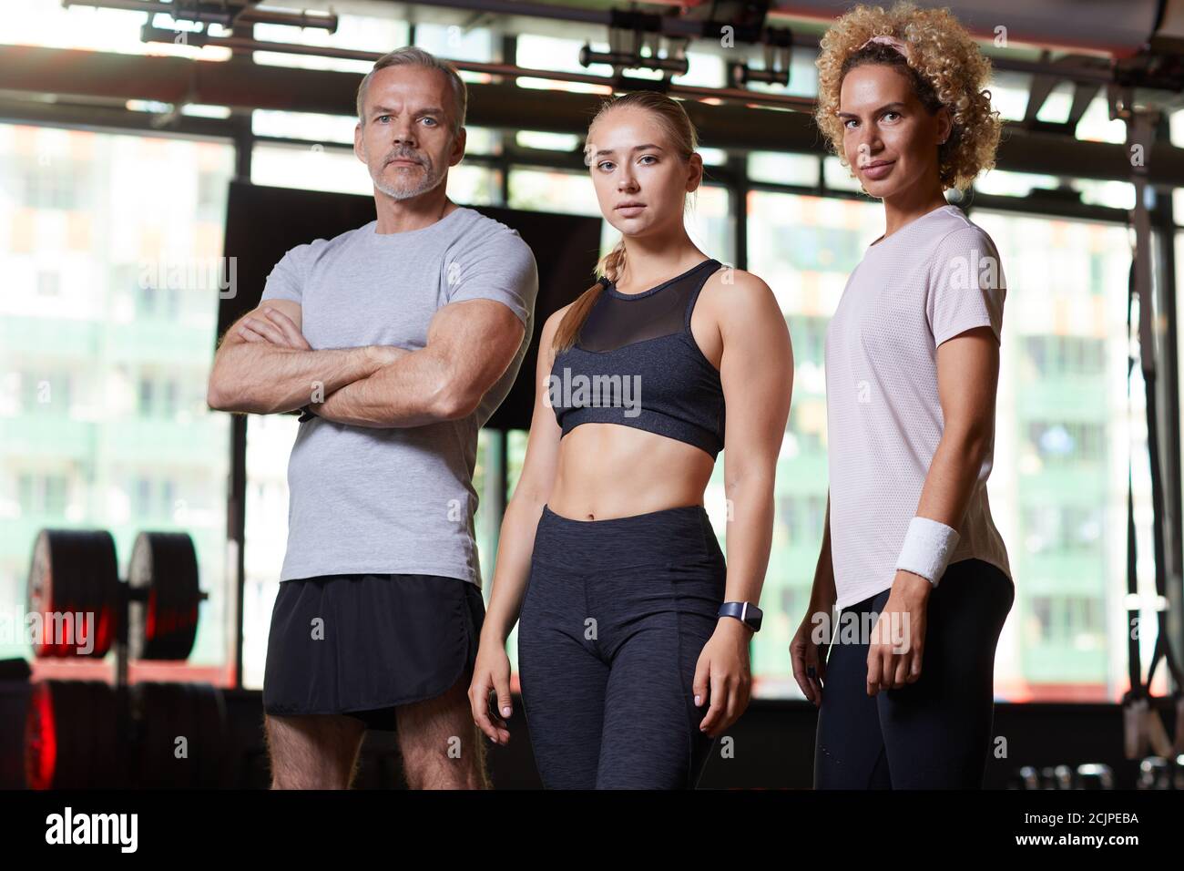 Gruppo di istruttori sportivi che guardano la fotocamera mentre si levano in piedi insieme nel centro benessere Foto Stock