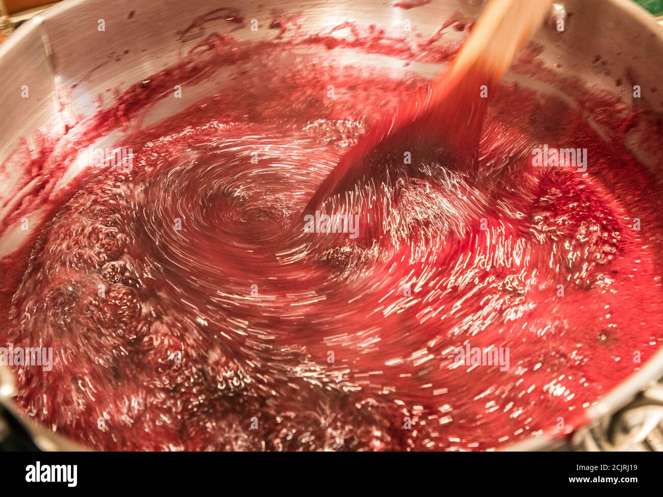 Preparare marmellata di more e pere, mescolando mentre si riscalda la frutta sul fornello in cucina casalinga, Regno Unito Foto Stock