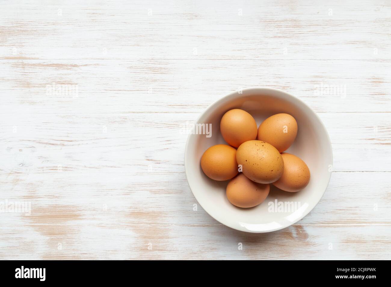 Vista dall'alto delle uova biologiche gratuite nel recipiente. Piatto con uova di pollo marroni su tavola di legno piatto. Far rosolare le uova nel recipiente sullo sfondo del legno Foto Stock
