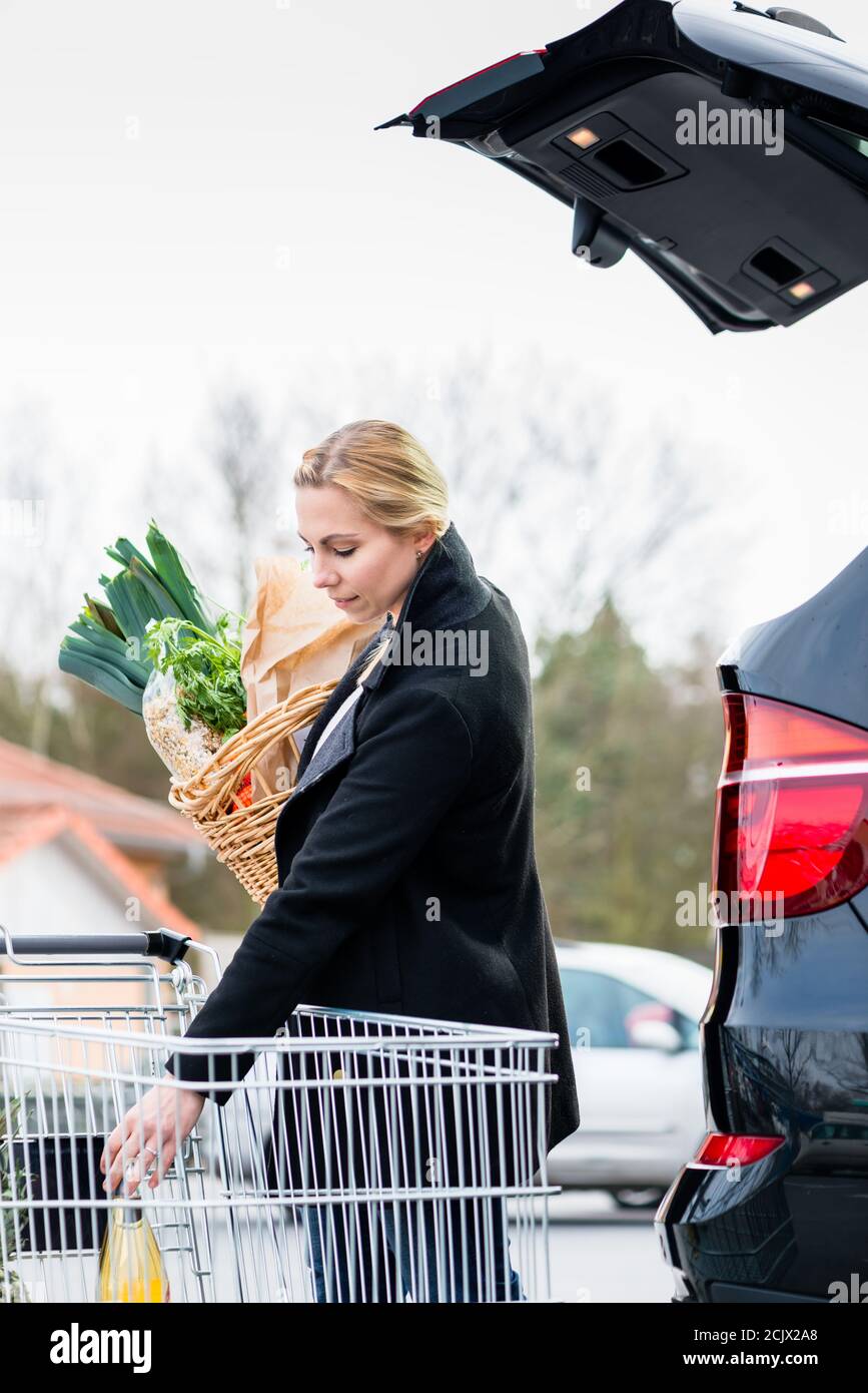 Donna che carica i generi alimentari dopo lo shopping nel tronco della sua auto Foto Stock