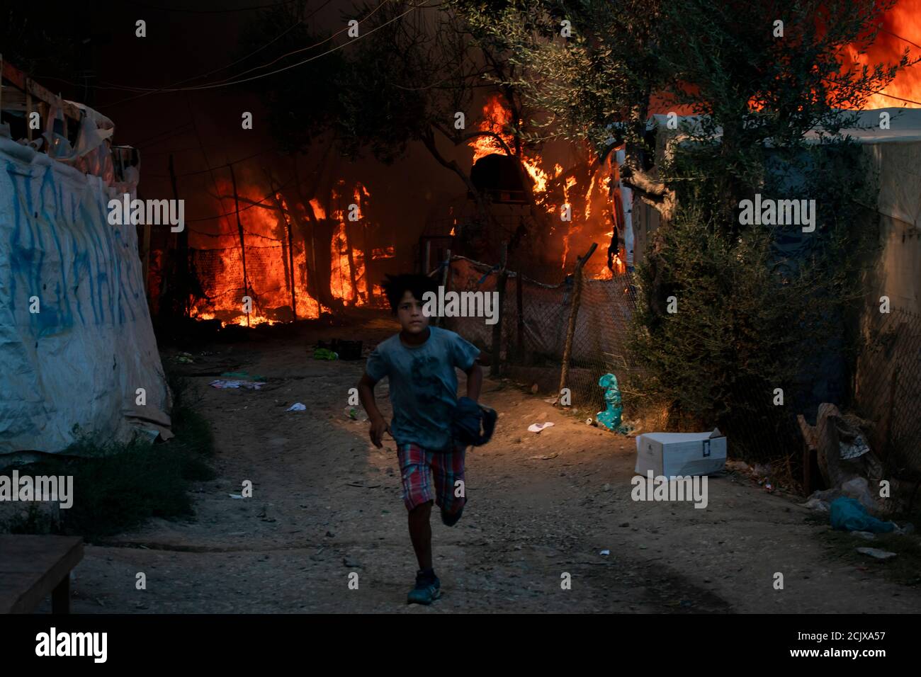 Un bambino fugge dal campo profughi di Moria dopo che gli incendi hanno completamente distrutto il campo mercoledì.migliaia di persone sono state costrette a fuggire dalle loro case dopo che un incendio scoppiò nel campo di Moria distruggendo le loro case e i loro beni. Foto Stock