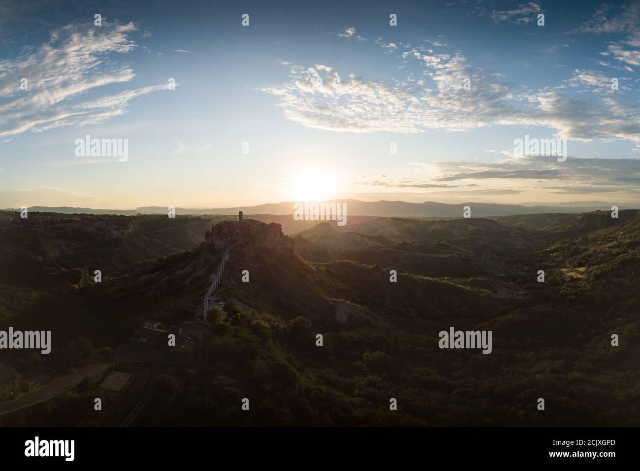 Veduta aerea della città in pietra Civita di Bagnoregio con il sole all'alba con i badlands di argilla e gli alberi dentro sfondo Foto Stock