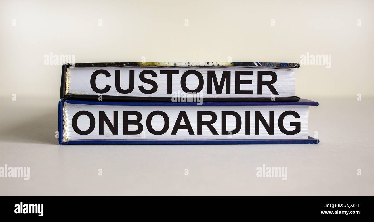 Libri con testo 'onboarding del cliente' su un bel tavolo bianco. Sfondo bianco. Concetto aziendale. Spazio di copia. Foto Stock