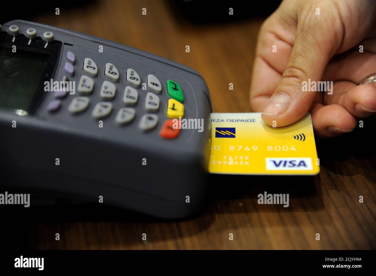 Il personale addetto alle vendite accetta il pagamento con carta di credito  tramite un dispositivo POS (Point-of-sale) presso un negozio boutique nel  centro di Atene, Grecia, il 10 maggio 2016. Foto scattata