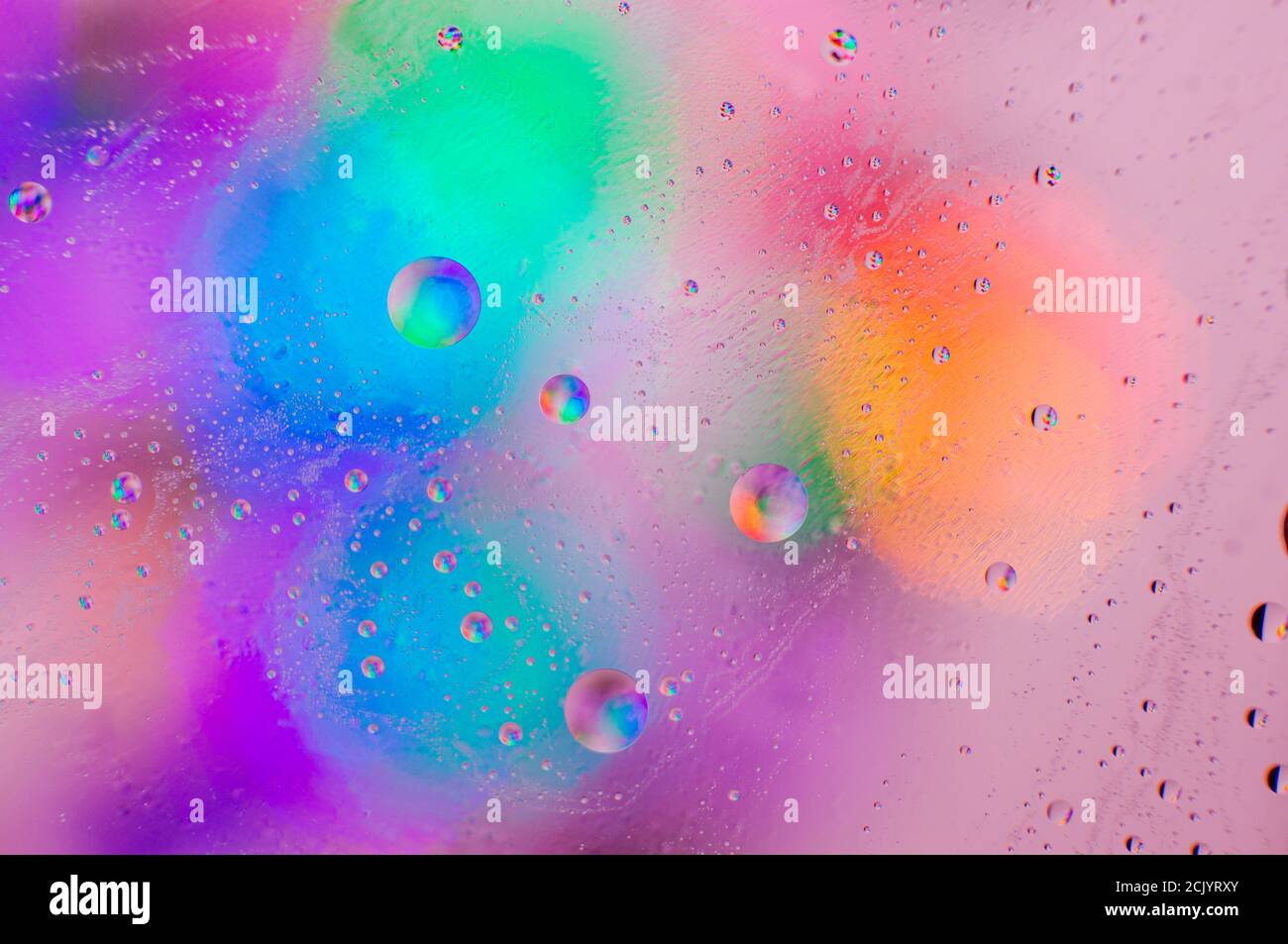 Iridescente sfondo macro astratto di gocce di olio in movimento sul superficie in vetro con bolle d'aria all'interno Foto Stock