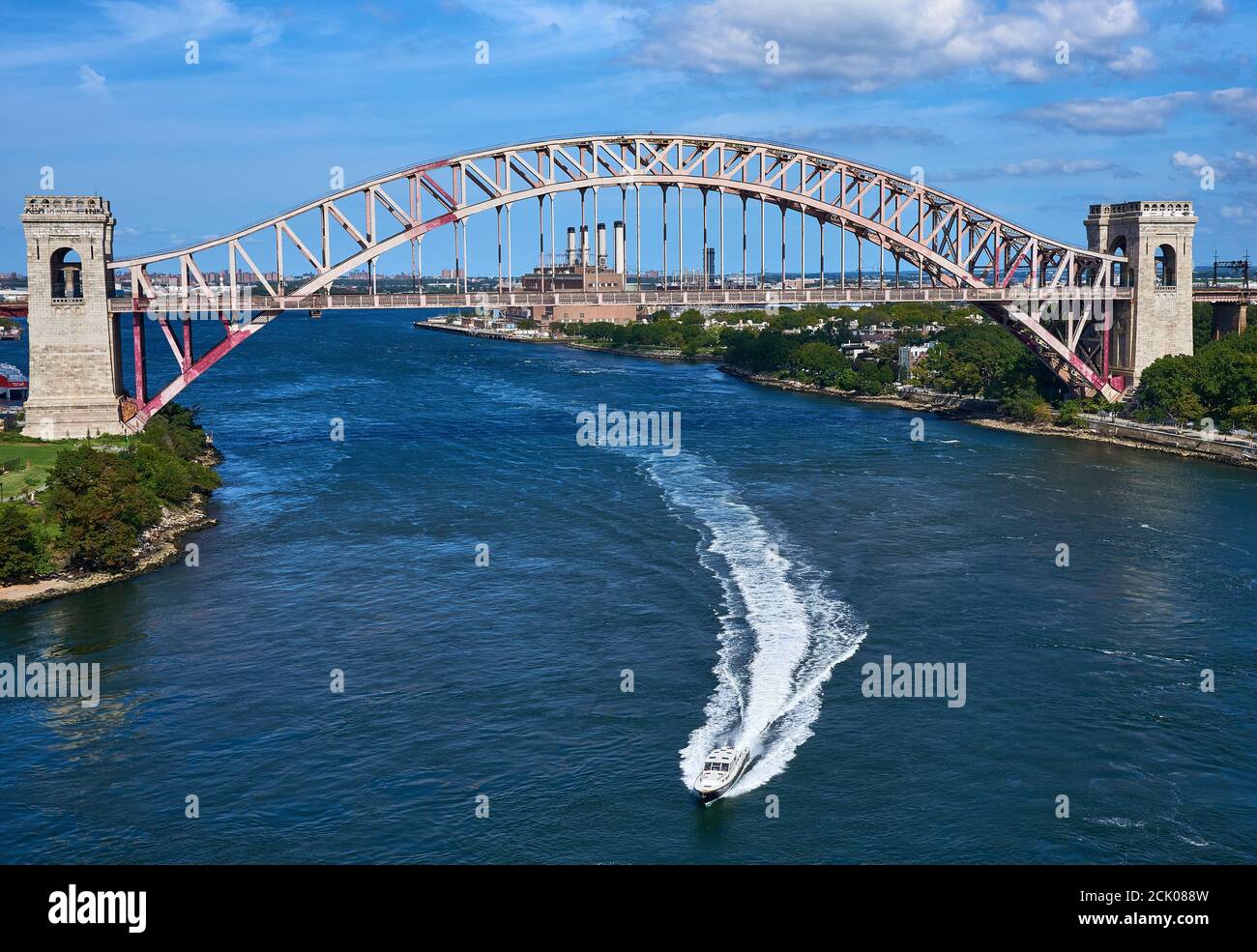 Il motoscafo lascia una scia mentre guida sotto il ponte ferroviario Hell Gate, attraverso l'East River, New York, New York. Foto Stock