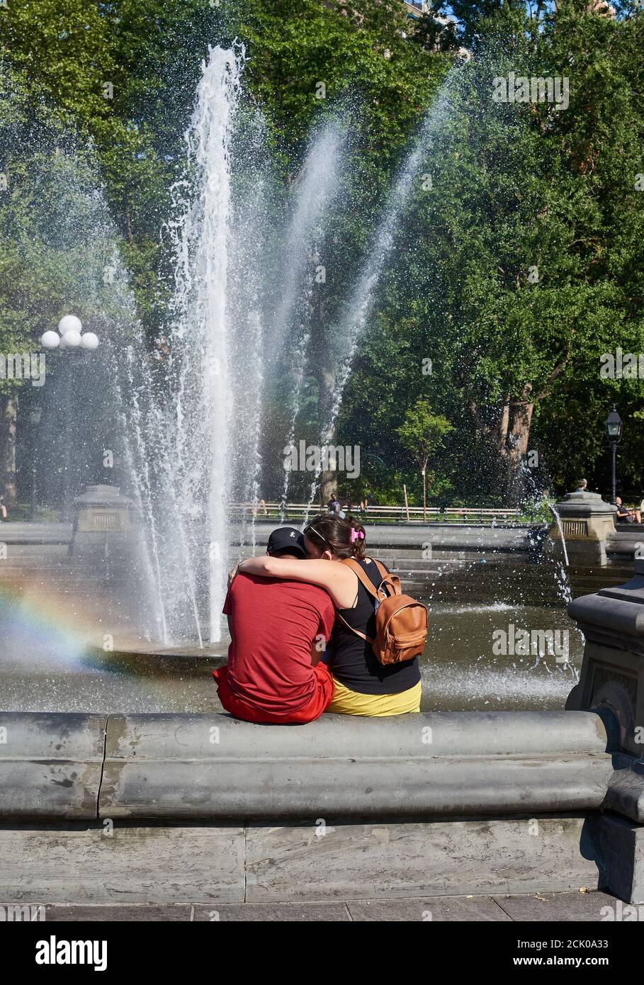 NEW YORK, NY - 8 SETTEMBRE 2020: Un abbraccio di coppia, come si siedono di fronte alla fontana in Washington Square Park. Foto Stock
