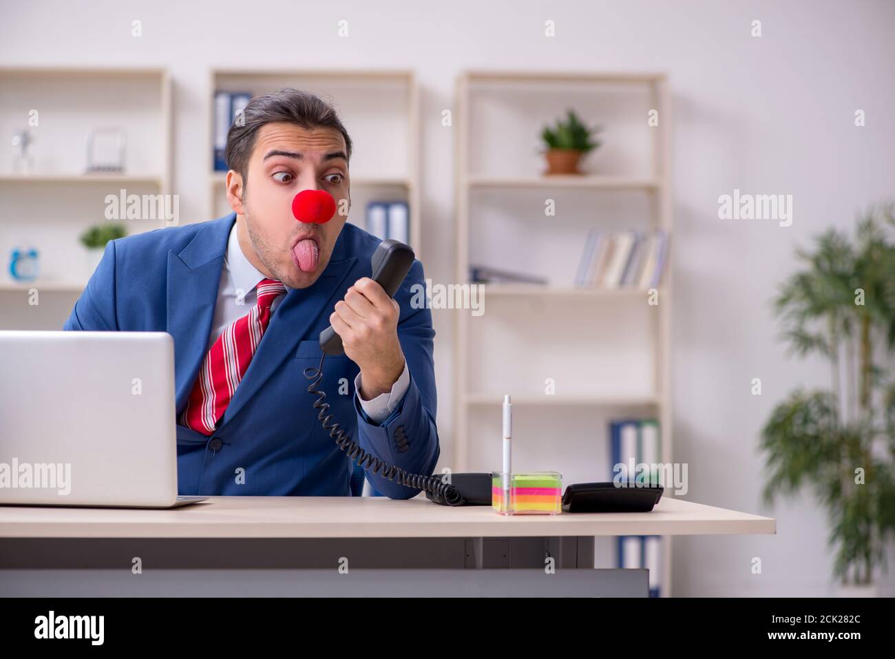 Divertente impiegato clown che lavora nella stanza dell'ufficio Foto Stock