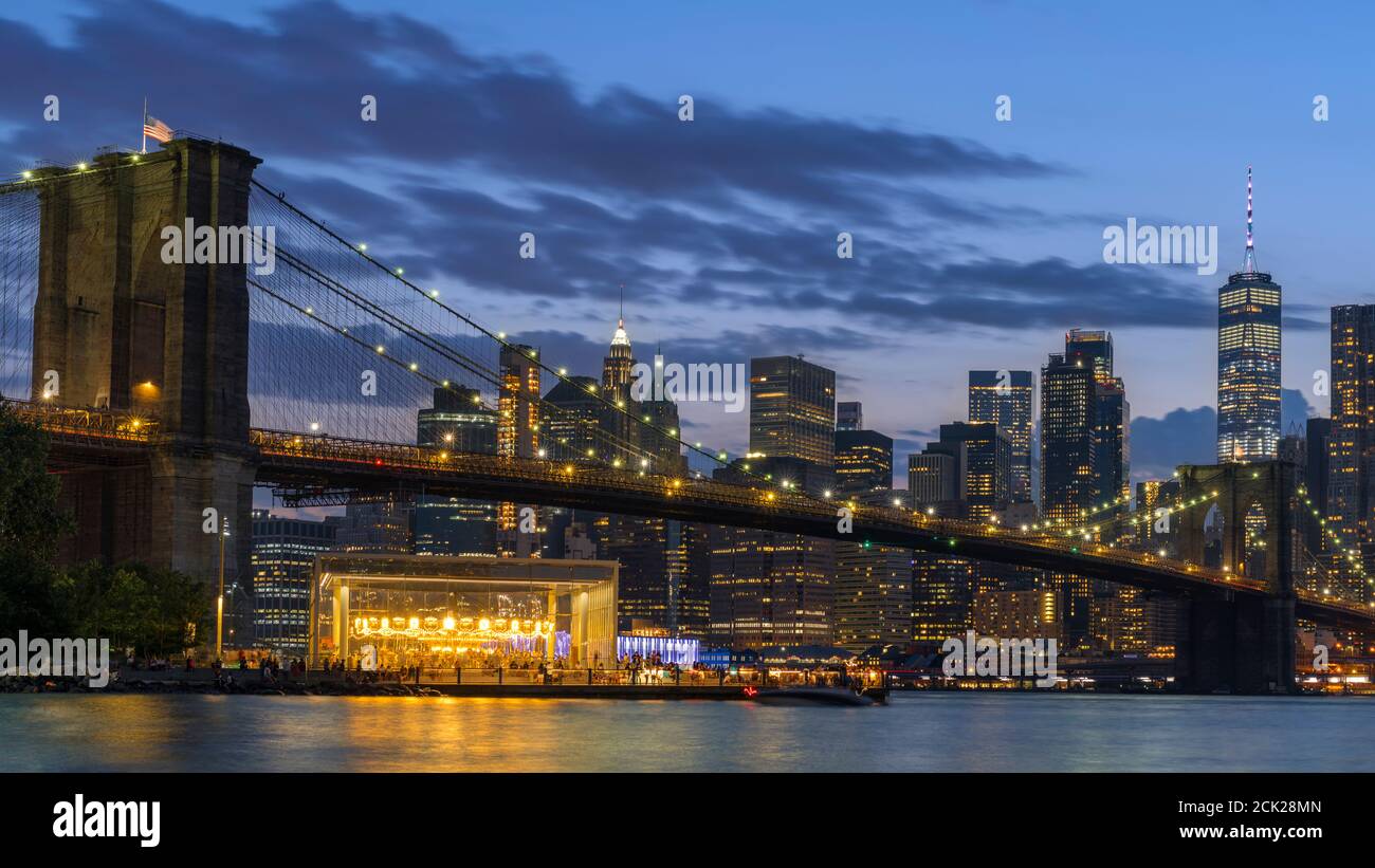 Ponte di Brooklyn e Lower Manhattan illuminati di notte. Vista da Main Street Park. Foto Stock