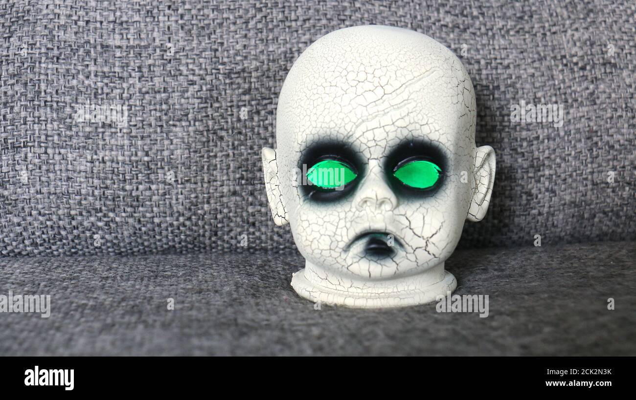 Testa della bambola creepy con gli occhi verdi incandescenti Foto Stock