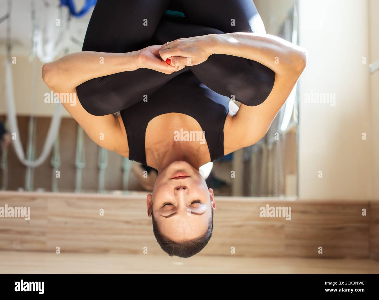 dormire nell'insolita pose.sportswoman si sta arricchiando mentre si appende nell'amaca blu. Foto Stock