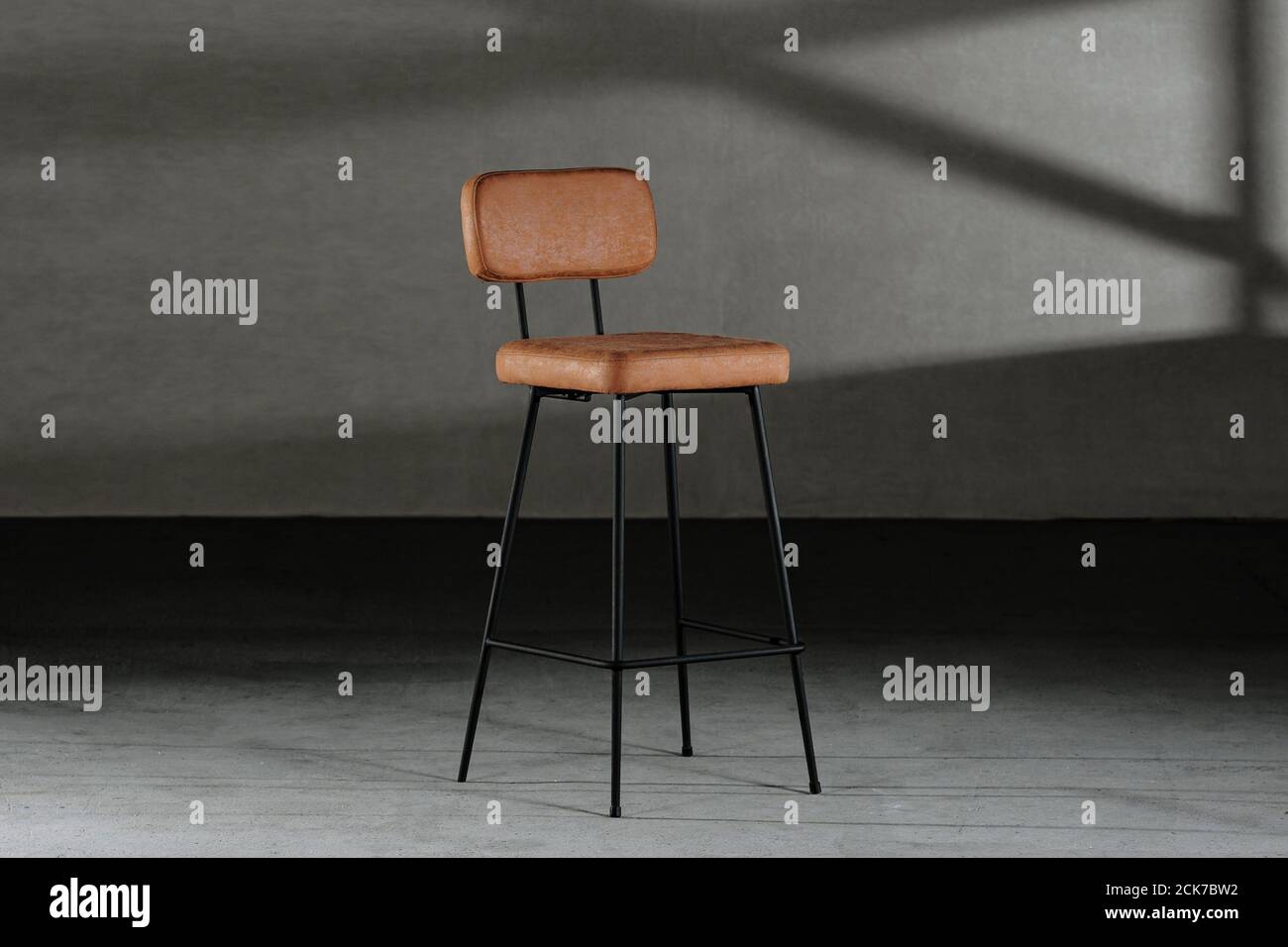 Primo piano di uno sgabello alto con rivestimento in pelle, su gambe sottili, mobili in stile loft Foto Stock