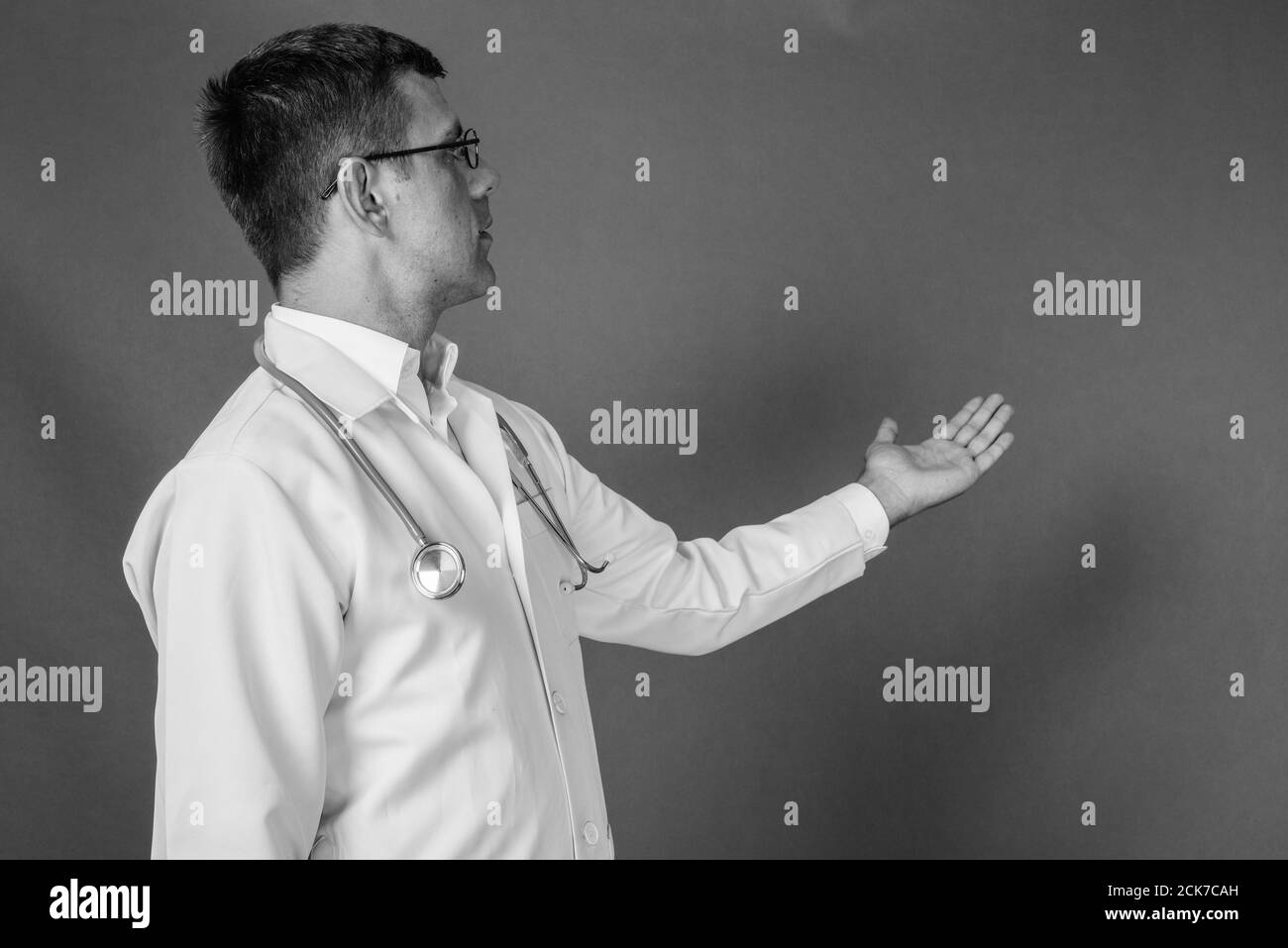 Uomo bello medico con capelli corti contro uno sfondo grigio Foto Stock