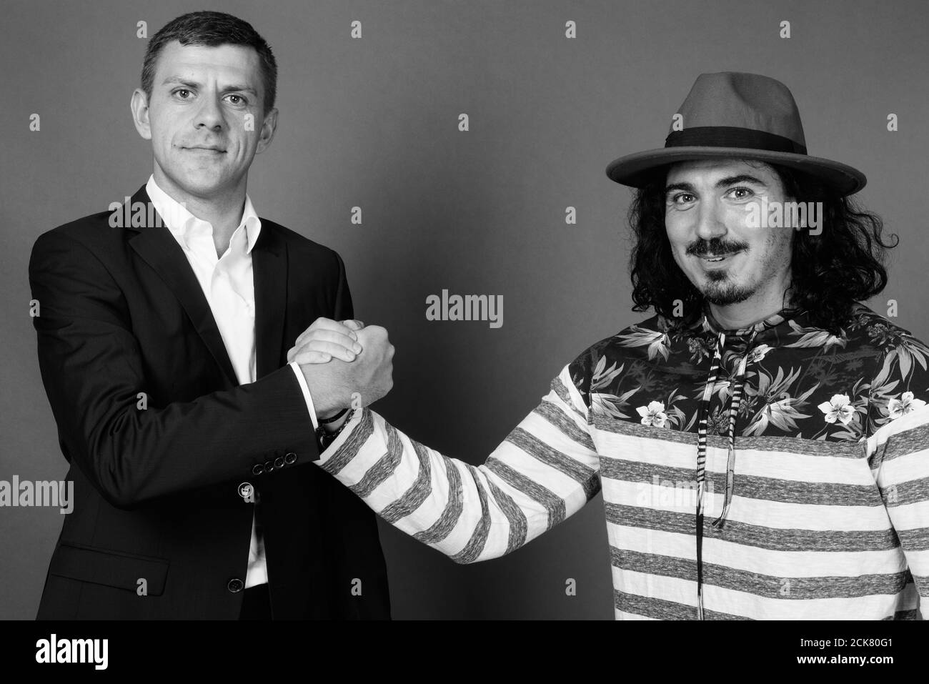 Uomo d'affari e bell'uomo con capelli ricci insieme contro grigio sfondo Foto Stock