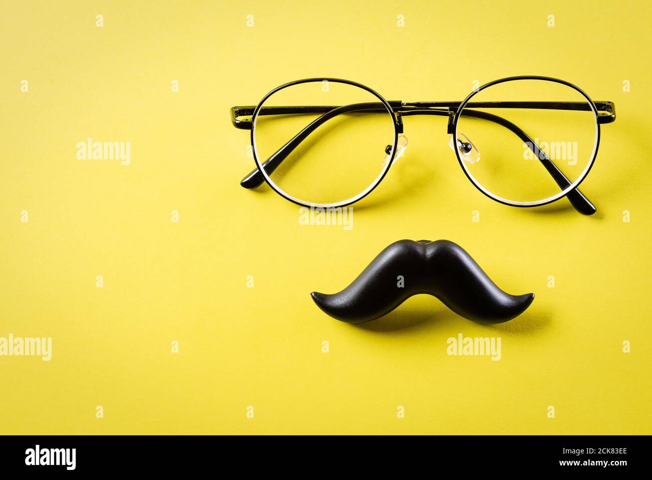 Concetto del giorno del Padre. Baffi neri e bicchieri su sfondo di carta giallo. Foto Stock