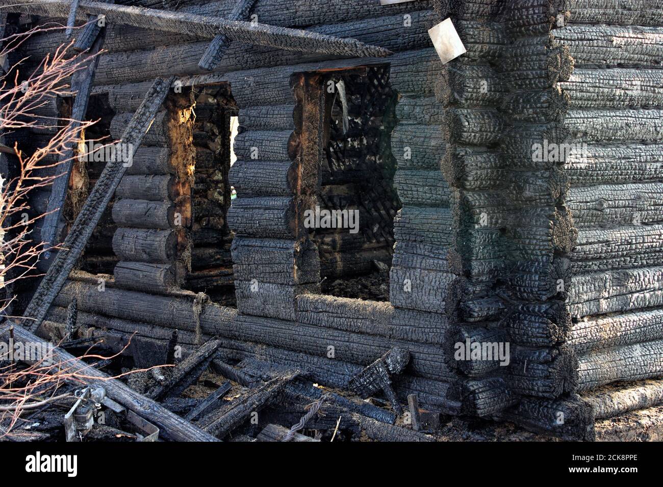 Dopo il fuoco - casa bruciata. Muri di legno bruciato nero, molto di tavole danneggiate e spazzatura. Giorno estivo soleggiato. Foto Stock