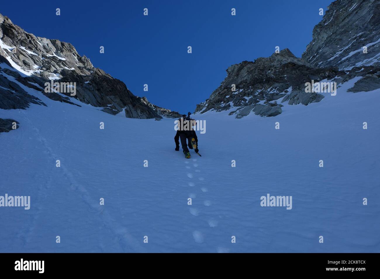 Scalata invernale con ramponi e ghiaccio, sci sul retro, couloir Anzévui, Aiguille de la TSA, Vallese, Svizzere Foto Stock