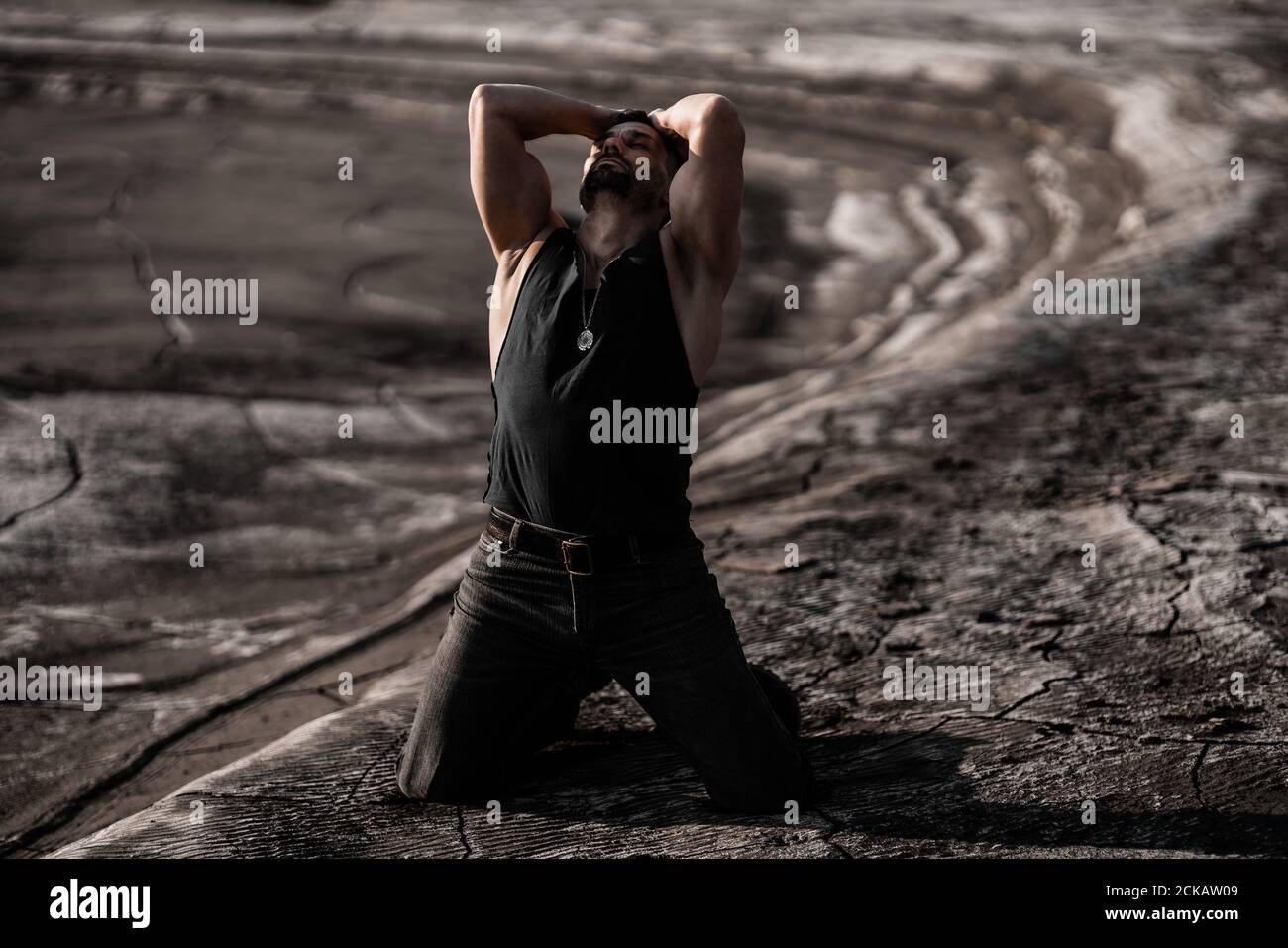 Attraente uomo abbronzato sulla sabbia nera Foto Stock