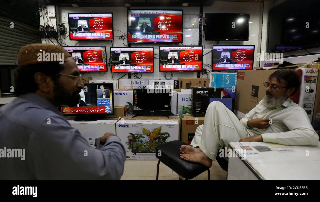 I negozianti parlano come schermi televisivi mostrano la copertura della revisione della Corte Mondiale della pena di morte data all'ex comandante della marina indiana Kulbhushan Sudhir Jadhav, in un negozio a Karachi, Pakistan 17 luglio 2019. REUTERS/Akhtar Soomro Foto Stock