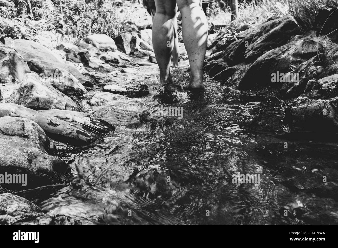 Primo piano di una persona in piedi su una cascata con pietre Foto Stock