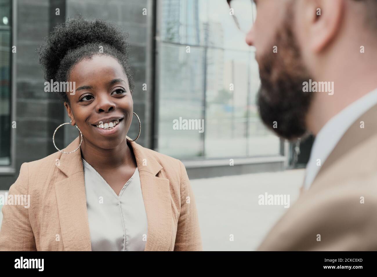 Giovane donna africana che parla con l'uomo e sorridendo mentre loro in piedi sulla strada in città Foto Stock