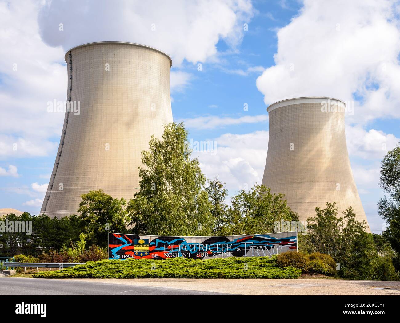 Segnale di benvenuto della centrale nucleare di Nogent-sur-Seine, Francia, gestita dalla società di servizi pubblici di energia elettrica EDF, e delle due torri di raffreddamento. Foto Stock