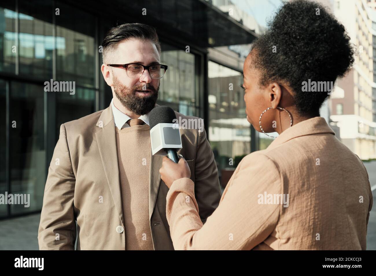 Donna africana con microfono che intervistano l'uomo mentre si levano in piedi in città Foto Stock