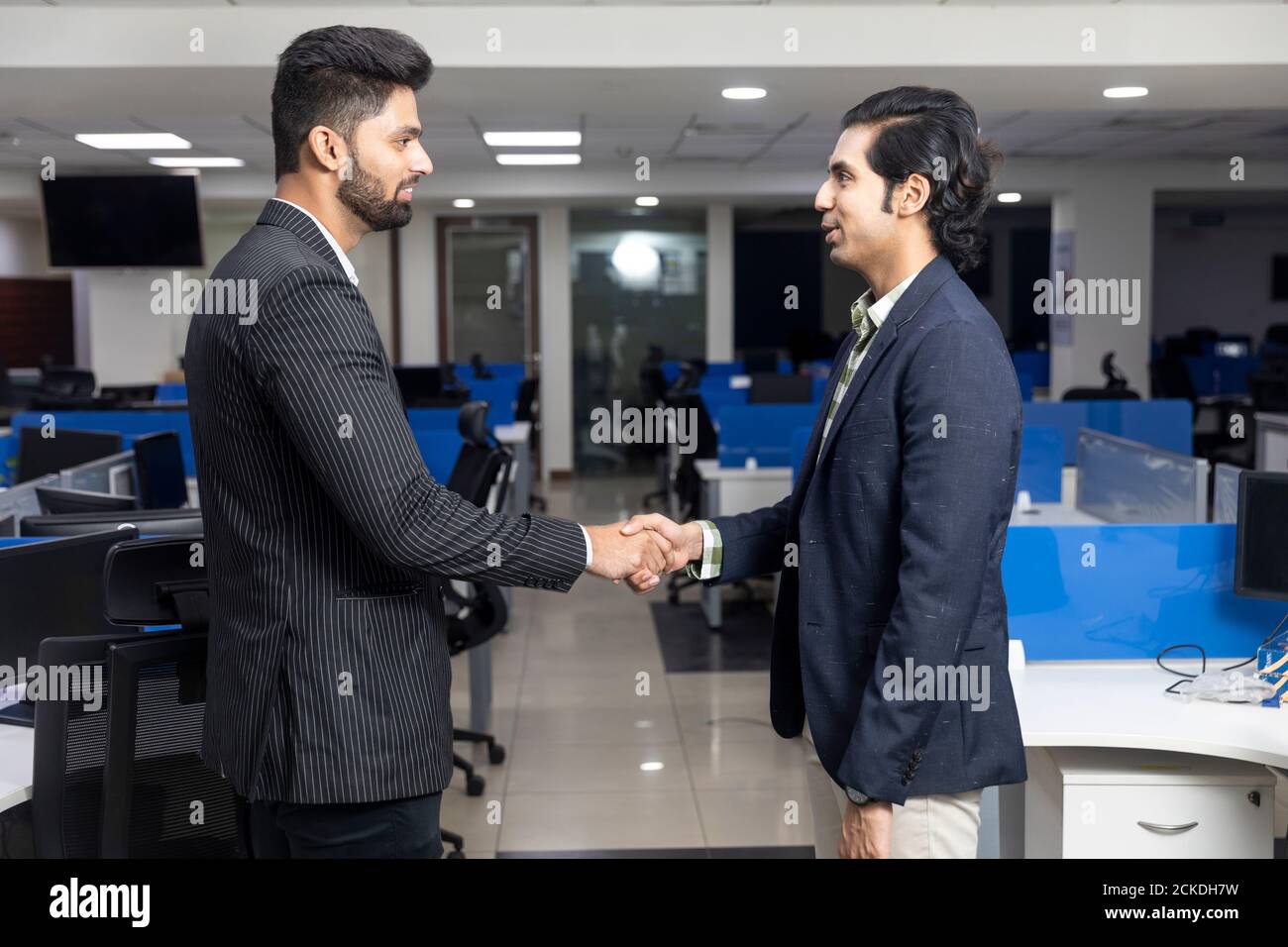 Ritratto di due giovani imprenditori indiani che scuotono le mani, raggiungere un accordo con il cliente, chiudere un accordo, ambiente aziendale, background ufficio. Foto Stock